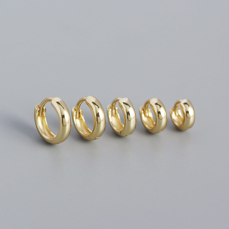 Five gold hoop earrings on a gray background