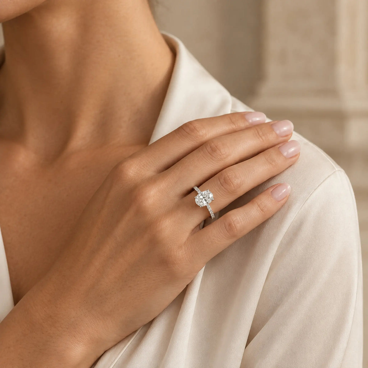 Woman wearing Aurelia oval moissanite engagement ring with an ivory silk blouse