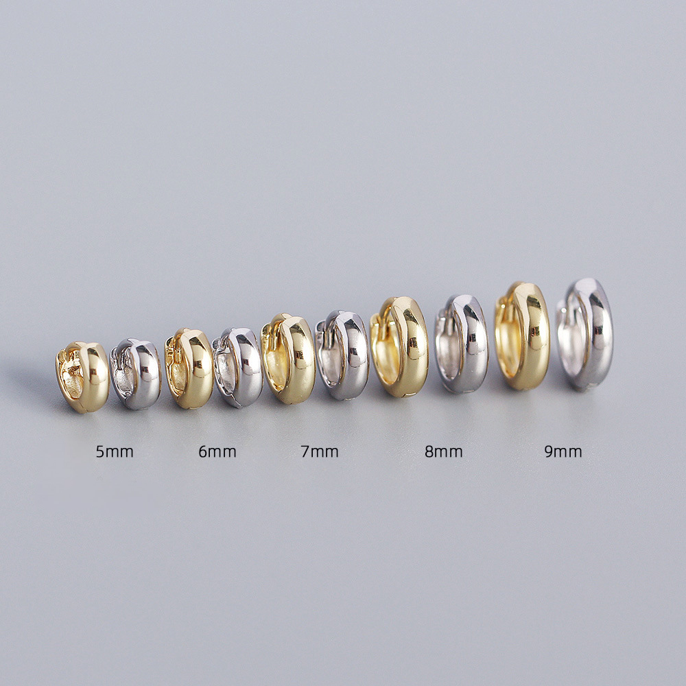 Set of gold and silver hoop earrings in various sizes on a gray background