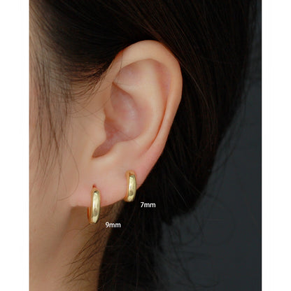 Gold hoop earrings worn on an ear with size labels '7mm' and '9mm'.