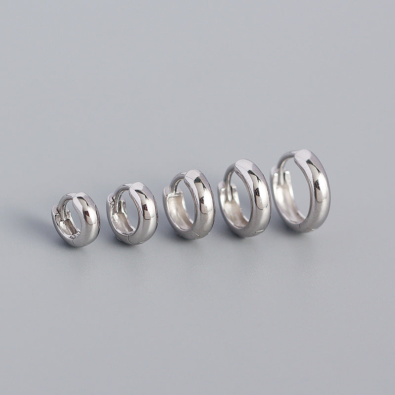 Set of five silver hoop earrings on a gray background