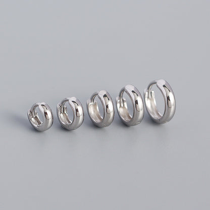 Set of five silver hoop earrings on a gray background