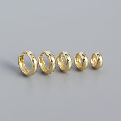 Five gold hoop earrings on a gray background