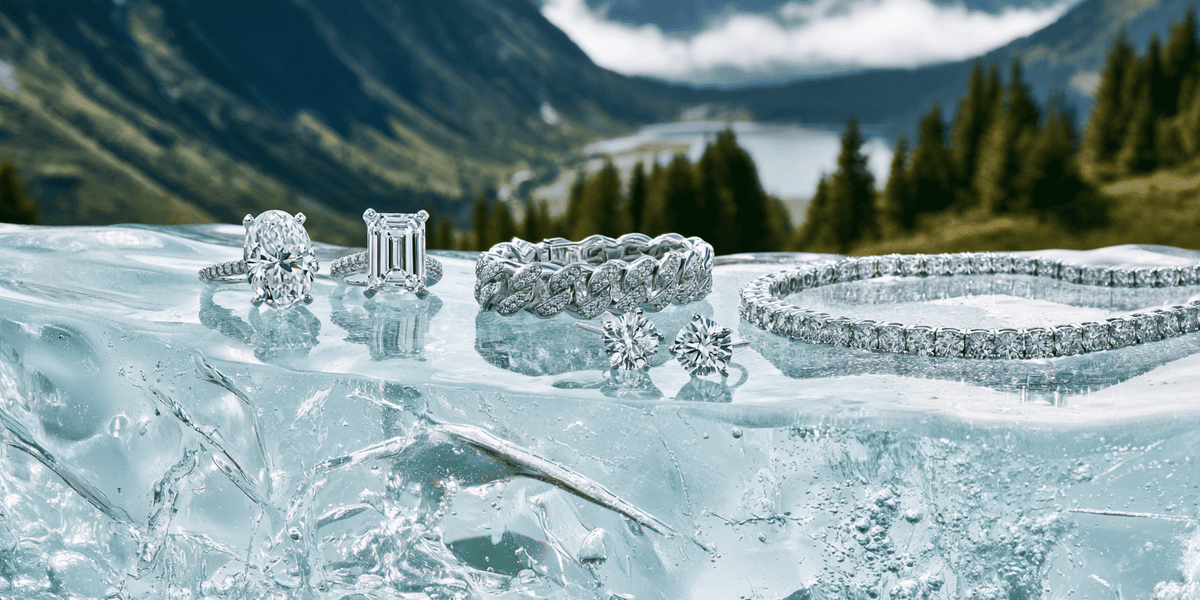 A collection of sparkling silver-toned diamond jewelry, including rings, a bracelet, and earrings, arranged on a bed of clear ice with a scenic mountain and lake background. ANNXMEE Jewelry