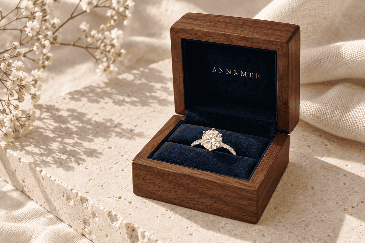Round moissanite ring in an ANNXMEE wooden jewelry box with dark blue velvet lining.